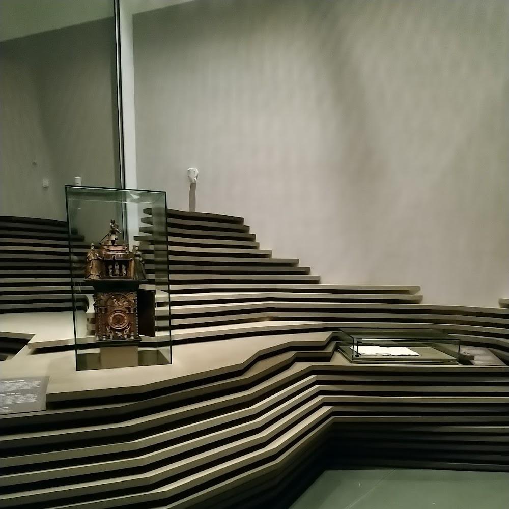A clock in a glass case and layered platform. The clock is the Astronomical Clock of Prague.
